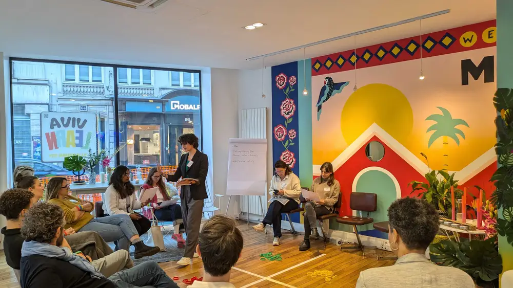 Une intervenante anime un atelier en cercle devant une fresque colorée